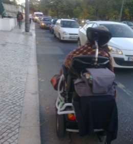 Foto de Raquel Rodrigues a deslocar-se pela estrada na sua cadeira de rodas devido à falta de passeio rebaixado.